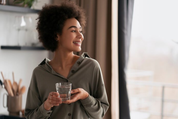 jovem sorridente em casa tomando um chá.