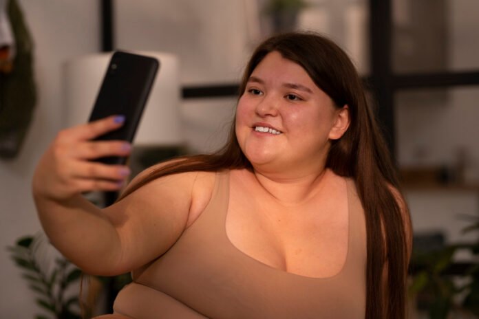 jovem acima do peso tirando uma selfie.