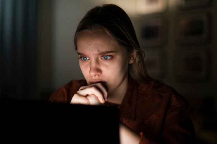 Uma jovem assustada lendo na tela do computador.