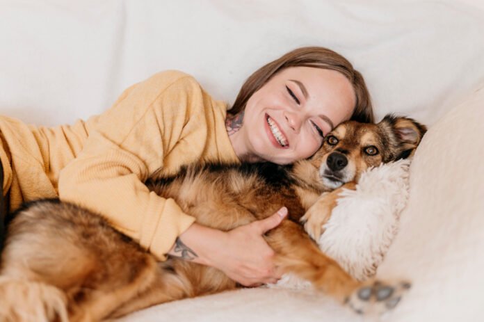 uma jovem deitada abraçada com seu cão.