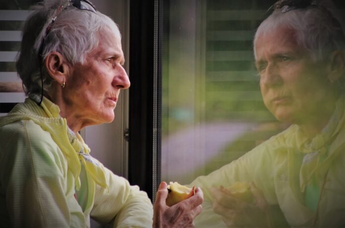 um idoso com Alzheimer olhando peça janela.