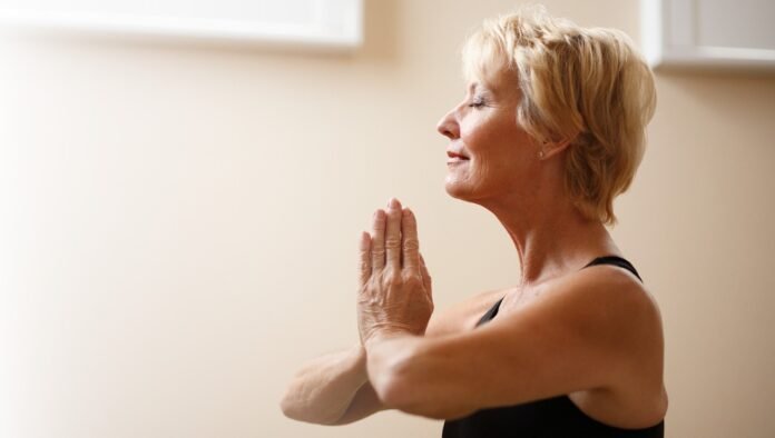 senhora sorridente praticando yoga.