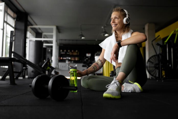 Uma atleta descansando sentada no chão da academia.