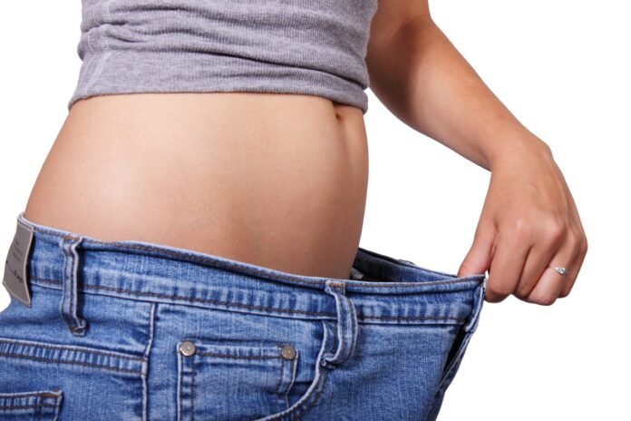 foto de uma jovem vestindo uma calca jeans varios numeros acima do seu.