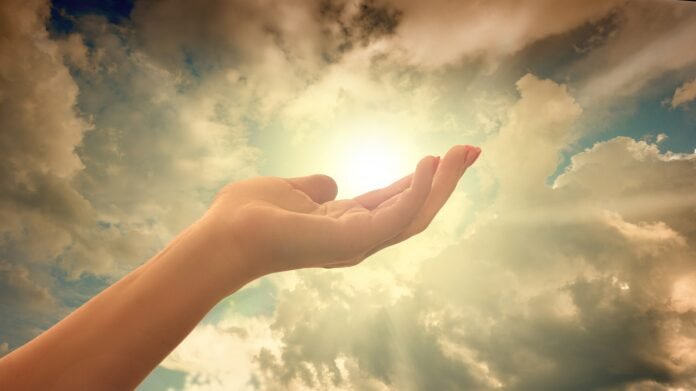 arte de uma mão elevada ao céu com um raio de luz brilhando entre as nuvens.