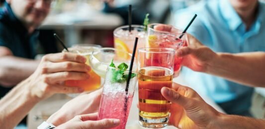 grupo de pessoas brindando com bebidas alcoólicas num bar.
