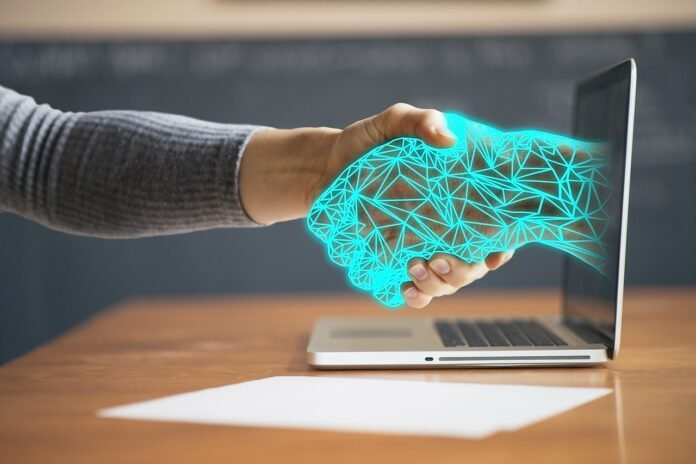 arte de uma mão humana cumprimentando uma mão cibernética que sai da tela de um computador.
