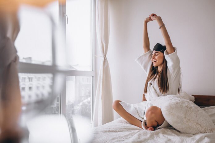 mulher acordando feliz na cama.