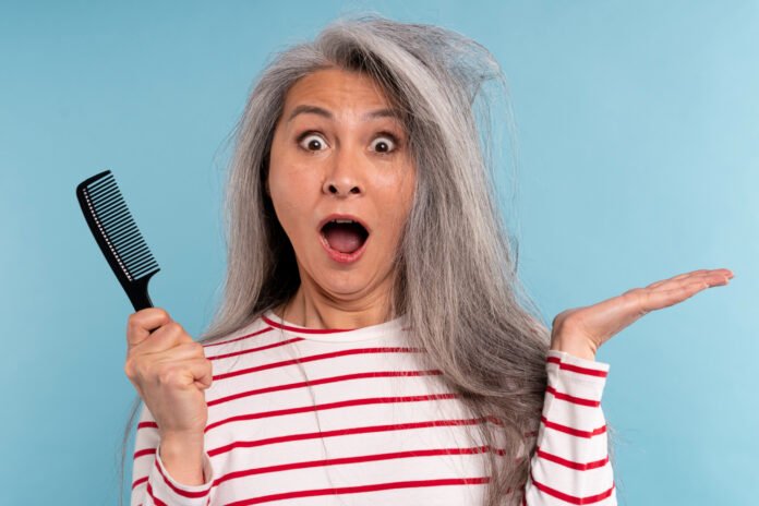 mulher com uma escova nas mãos assustada com a queda de cabelo