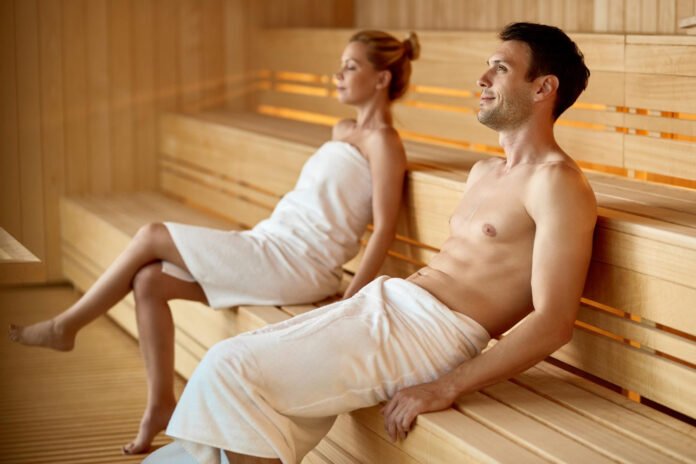 um homem e uma mulher de toalhas brancas em uma sauna seca.
