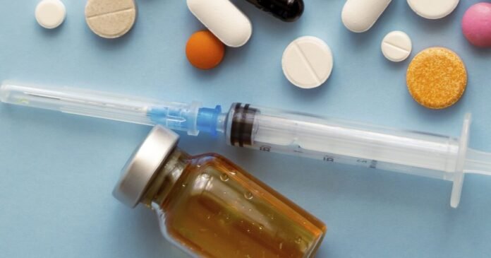 imagem de vários medicamentos de varias cores, uma seringa e um pequeno vidro marrom de remédio injetável.