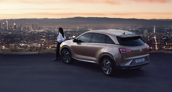 foto de um hyundai NEXO em um mirante tendo uma cidade ao fundo e uma mulher sentadada