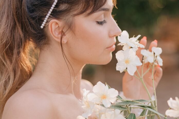 uma jovem com uma tiara de flores, sentindo o cheiro de uma flor