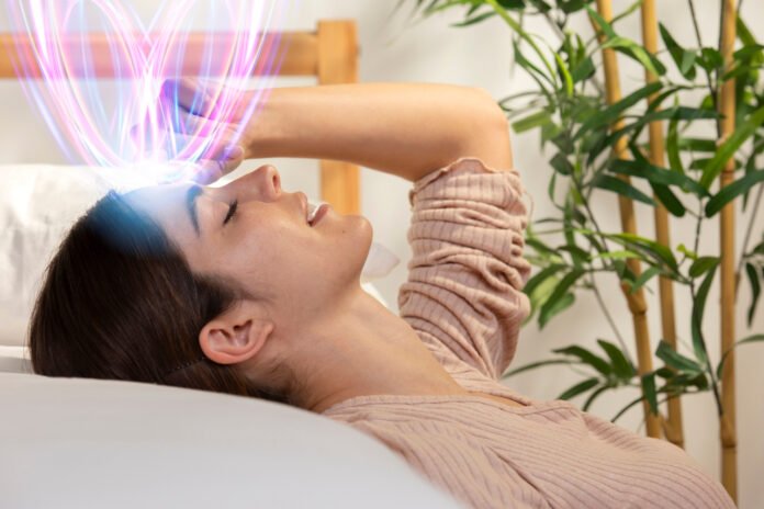 Tronco e cabeça de uma jovem deitada de olhos fechados e ondas cerebrais coloridas saindo da sua cabeça.