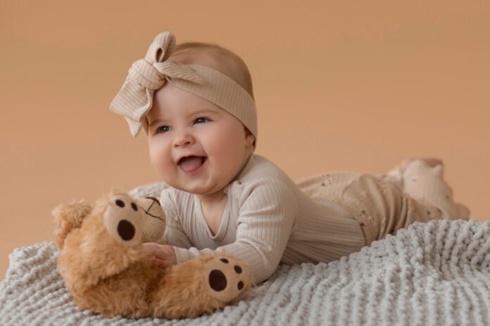 uma bebe feminina, de roupa marrom e laco na cabeça, deitada com seu tigre de pelúcia.