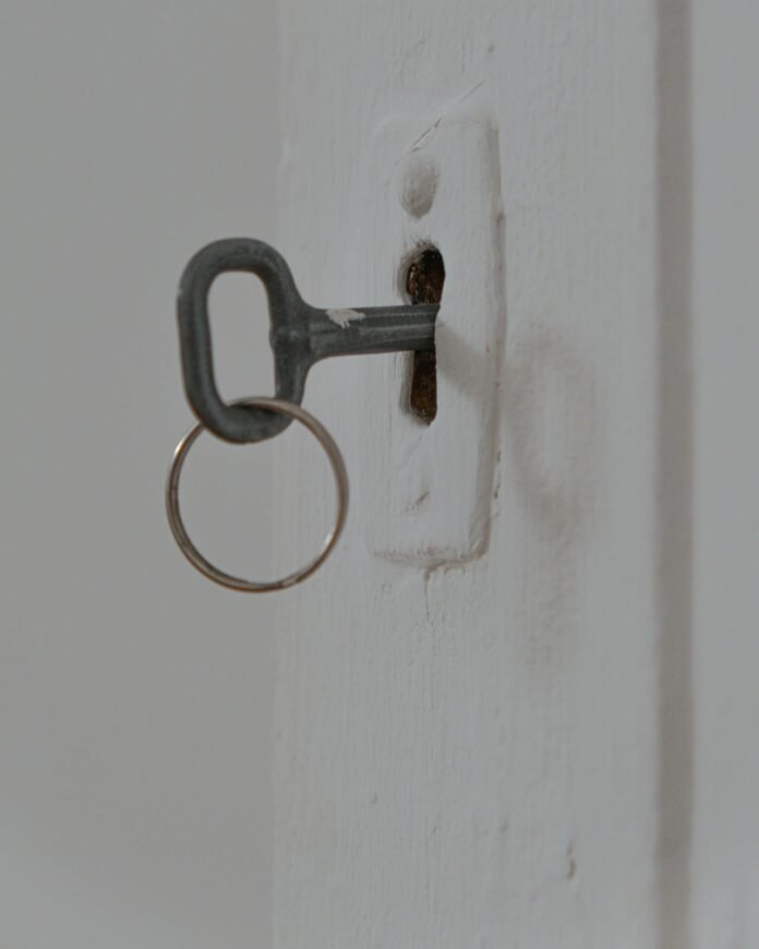 porta antiga pintada de branco com uma chave na fechadura.