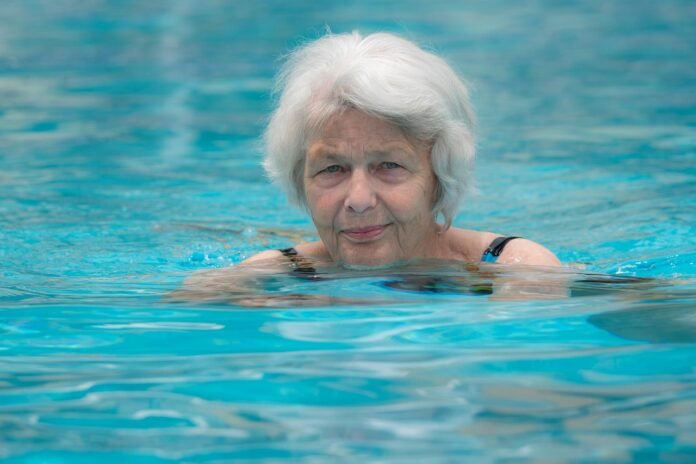 uma senhora idosa em trajes de banho em uma piscina.