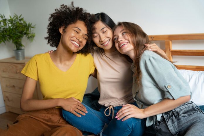 3 amigas abraçadas, sentadas num banco.