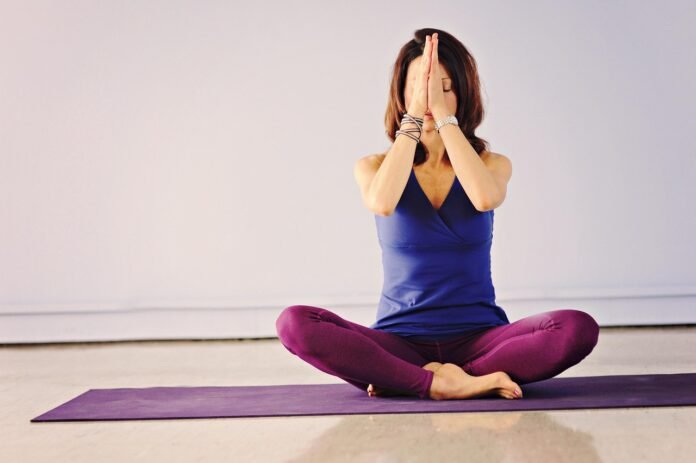 mulher praticando yoga, sentada em posição de meditação.