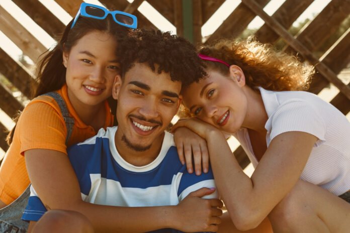 três jovens abraçados.