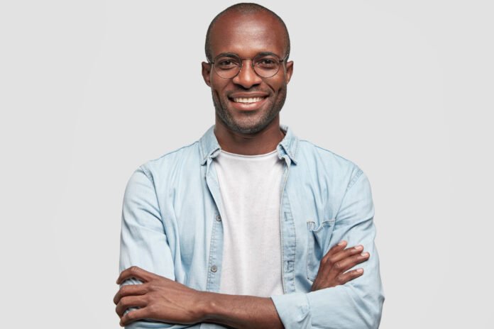 homem negro de braços cruzados em primeiro plano.