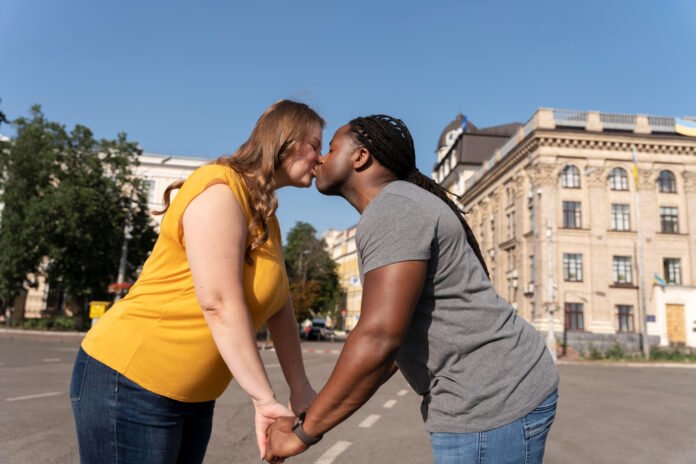 casal interracial se beijando em uma praça.