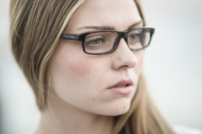 close de uma mulher jjovem com óculos preto retangular