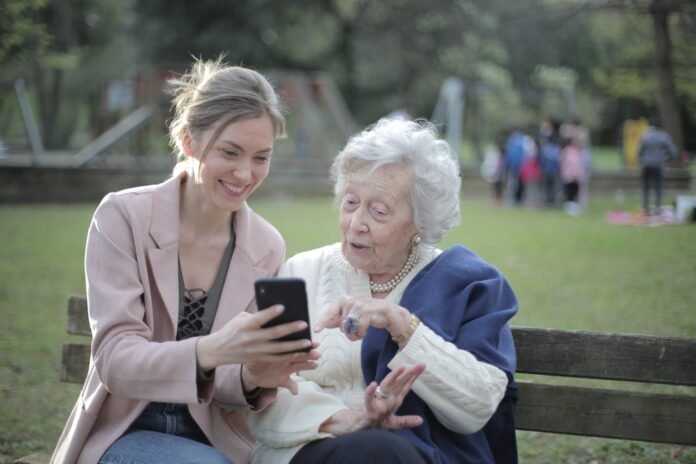 uma mulher jovem com uma idosa, sentada num banco ao ar livre