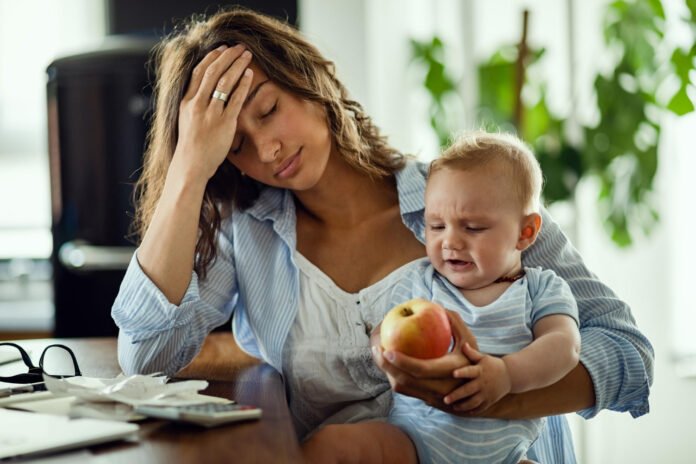 mãe com sintomas de depressão com o bebê no colo.