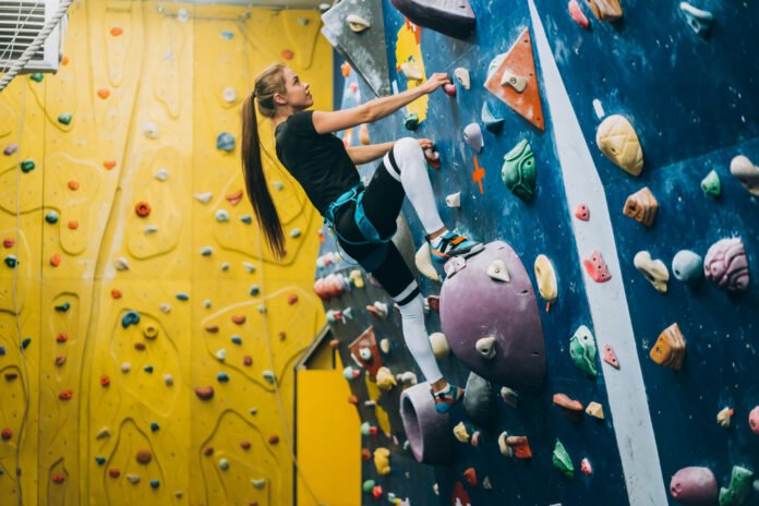 uma jovem praticando escalada indoor.