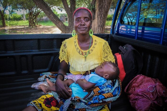 Mae africana com se bebê no colo.
