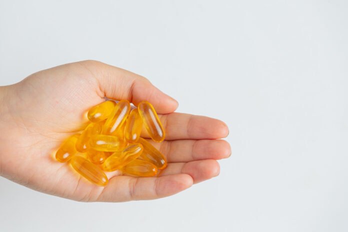 mão contendo varias capsulas de óleo de peixe.
