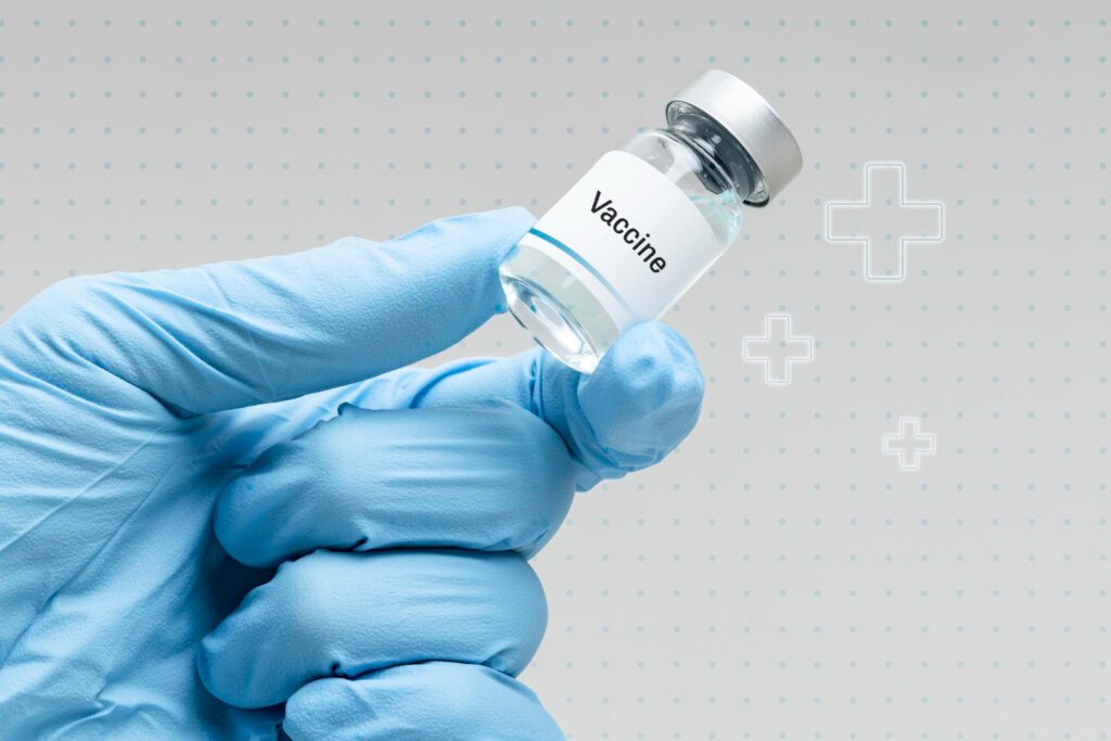 mão com luvas azuis segurando uma ampola de vacina.